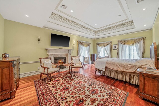 184-61 Radnor Rd, Jamaica Estates, NY 11432 - bedroom featuring crown molding, light wood-type flooring, a glass covered fireplace, and a tray ceiling