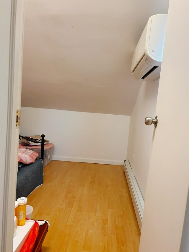 54-23 153rd St, Flushing, NY 11355 - bedroom with a baseboard heating unit, light wood-style floors, a wall mounted AC, lofted ceiling, and baseboards
