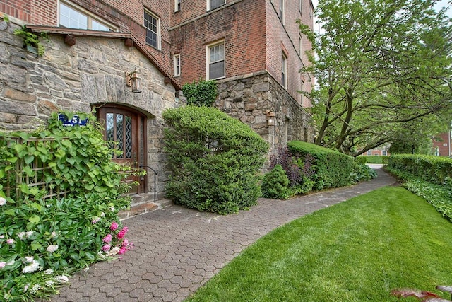 151 Centre Ave Unit 5D, New Rochelle, NY 10805 - view of exterior entry featuring stone siding, brick siding, and a lawn