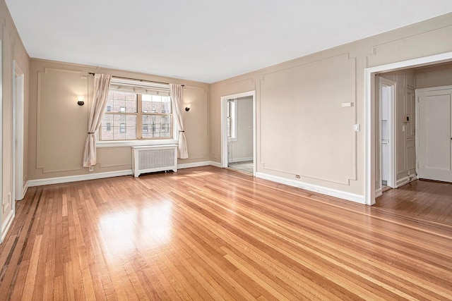 151 Centre Ave Unit 5D, New Rochelle, NY 10805 - empty room featuring radiator, light wood-style flooring, a decorative wall, and baseboards