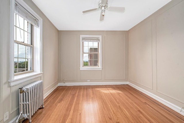 151 Centre Ave Unit 5D, New Rochelle, NY 10805 - spare room featuring radiator, a decorative wall, light wood-style flooring, plenty of natural light, and a ceiling fan