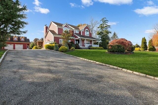 140 Grant Dr, Aquebogue, NY 11931 - view of front of home featuring a garage, covered porch, a front lawn, and a chimney