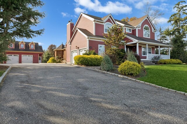140 Grant Dr, Aquebogue, NY 11931 - view of front facade with a garage, a porch, a chimney, and a front lawn