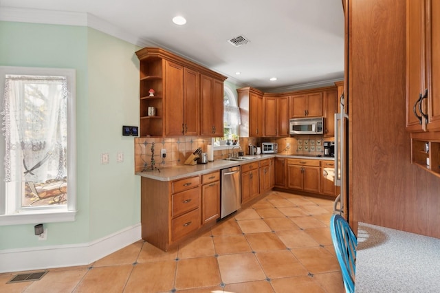 140 Grant Dr, Aquebogue, NY 11931 - kitchen with appliances with stainless steel finishes, light countertops, a sink, tasteful backsplash, and brown cabinets