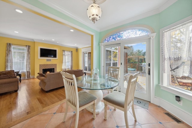 140 Grant Dr, Aquebogue, NY 11931 - dining area featuring crown molding, a fireplace, baseboards, recessed lighting, and light tile patterned floors