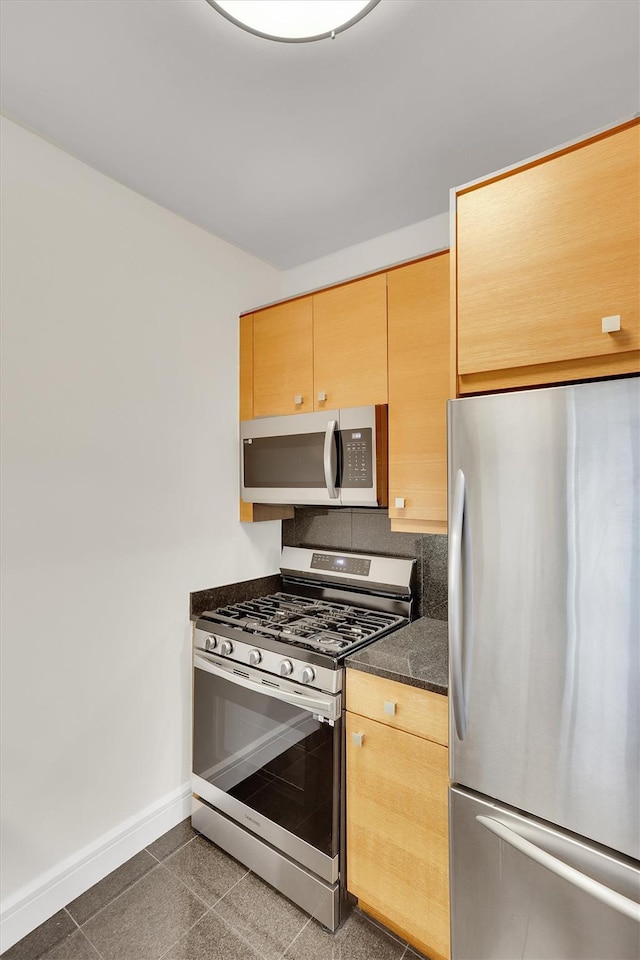 120 Riverside Blvd Unit 10T, New York Manhattan, NY 10069 - kitchen featuring stainless steel appliances, baseboards, dark countertops, granite floors, and light brown cabinetry
