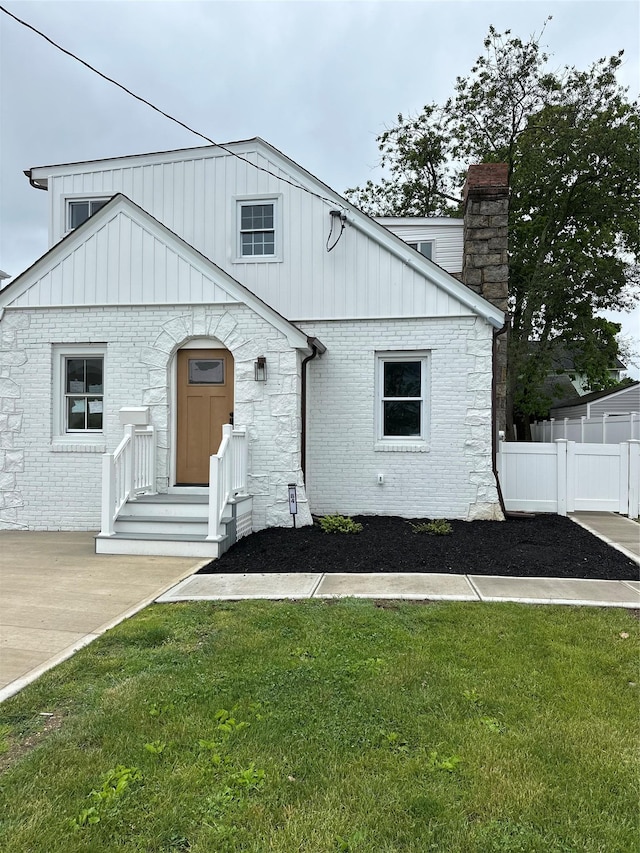 84 Windsor, Hempstead, NY 11550 - view of front facade featuring a chimney, board and batten siding, and brick siding