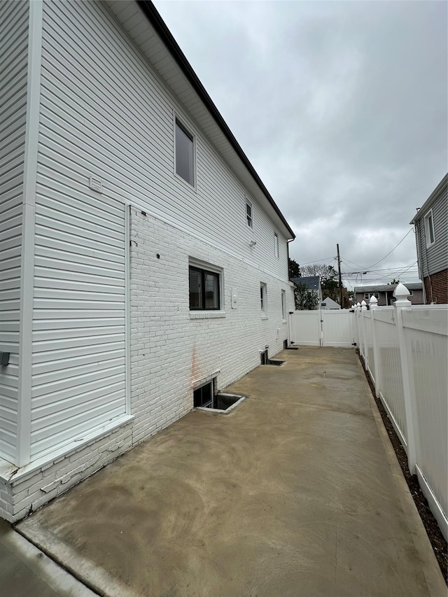 84 Windsor, Hempstead, NY 11550 - view of home's exterior with a fenced backyard, a patio area, brick siding, and a gate