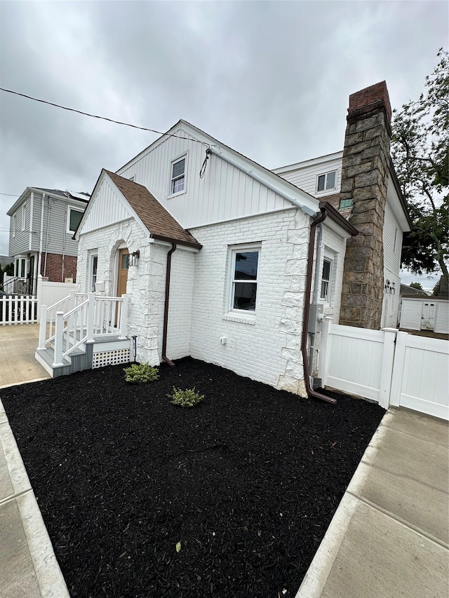 84 Windsor, Hempstead, NY 11550 - view of front of house featuring a chimney, stone siding, and board and batten siding