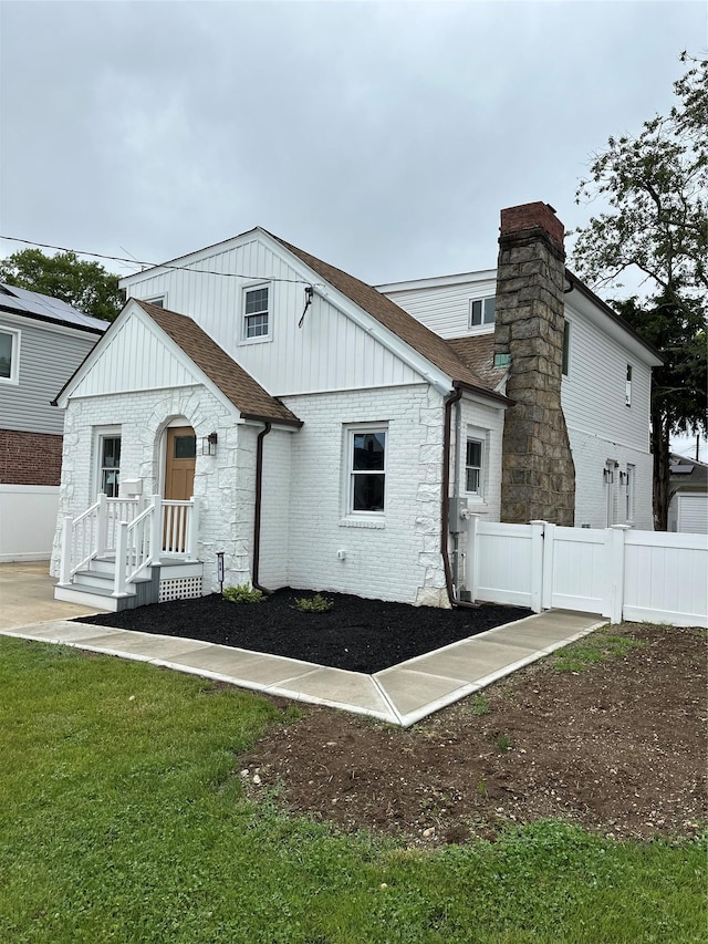 84 Windsor, Hempstead, NY 11550 - rear view of house featuring board and batten siding, roof with shingles, brick siding, and a chimney