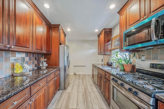 1668 Atherton Ave, Elmont, NY 11003 - kitchen with stainless steel appliances, light wood-type flooring, recessed lighting, decorative backsplash, and dark stone counters
