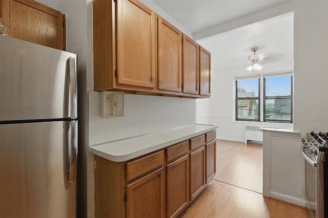 70 Sherman Ave Unit 2G, Yonkers, NY 10705 - kitchen with appliances with stainless steel finishes, radiator heating unit, light wood finished floors, light countertops, and brown cabinetry