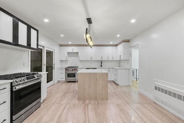 10 Karow Ct, Monsey, NY 10952 - kitchen featuring radiator heating unit, stainless steel range with gas cooktop, designer range, a kitchen island, and light countertops