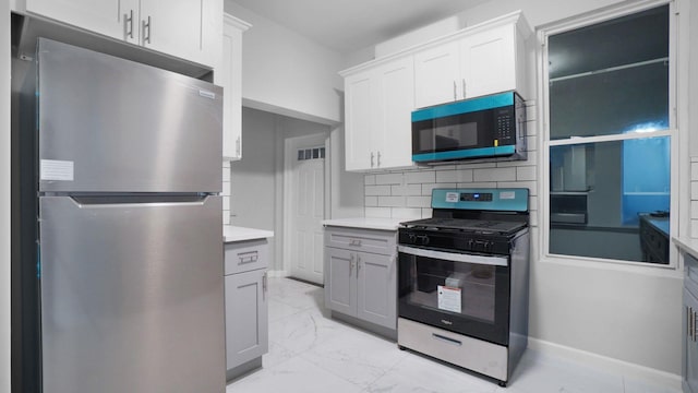 2448 Webb Ave, Bronx, NY 10468 - kitchen featuring stainless steel appliances, light marble finish flooring, light countertops, backsplash, and white cabinetry