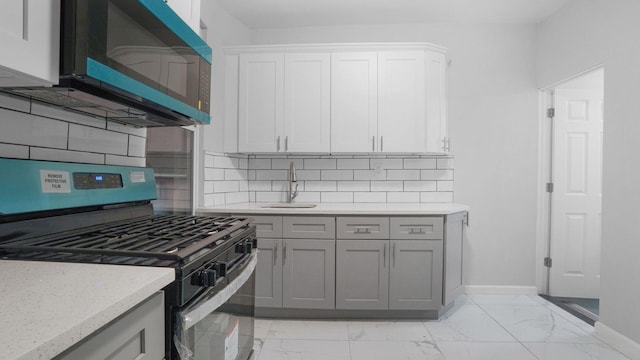 2448 Webb Ave, Bronx, NY 10468 - kitchen featuring gas stove, a sink, light marble finish floors, and baseboards