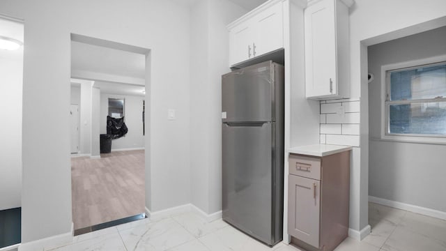 2448 Webb Ave, Bronx, NY 10468 - kitchen featuring freestanding refrigerator, light marble finish flooring, white cabinets, baseboards, and light countertops