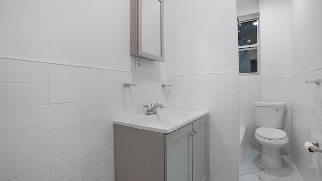 2448 Webb Ave, Bronx, NY 10468 - bathroom with tile walls, toilet, vanity, and a wainscoted wall