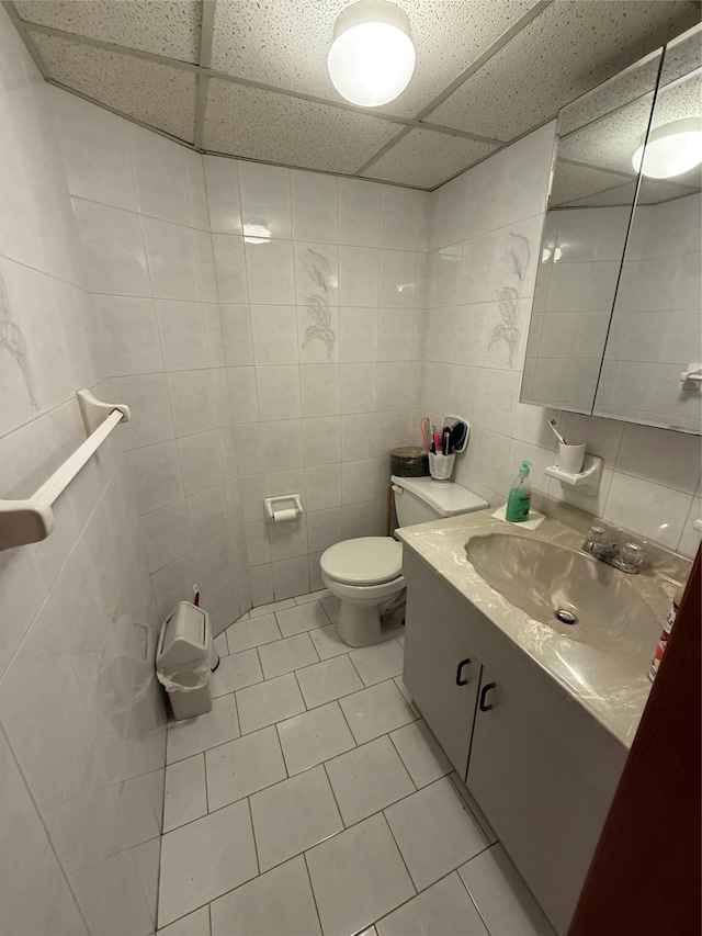 7542 67th Rd, Middle Village, NY 11379 - bathroom with tile walls, a paneled ceiling, tile patterned flooring, vanity, and toilet