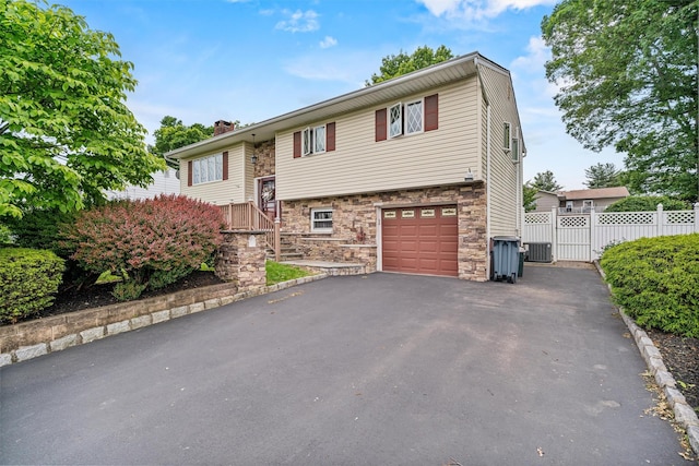23 Waldron Dr, Stony Point, NY 10980 - raised ranch featuring stone siding, central AC unit, asphalt driveway, a garage, and a chimney