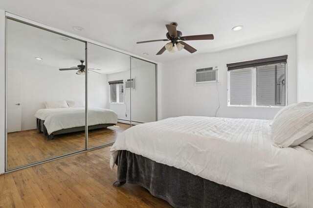 360 Robyn Pl, East Meadow, NY 11554 - bedroom featuring a baseboard radiator, an AC wall unit, hardwood / wood-style flooring, a closet, and ceiling fan