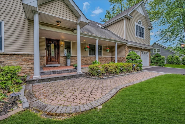 32 Robinhood Ln, East Setauket, NY 11733 - entrance to property featuring driveway, covered porch, an attached garage, a lawn, and stone siding