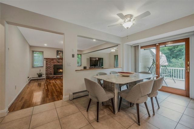 32 Robinhood Ln, East Setauket, NY 11733 - dining space featuring a baseboard radiator, healthy amount of natural light, a brick fireplace, and baseboards
