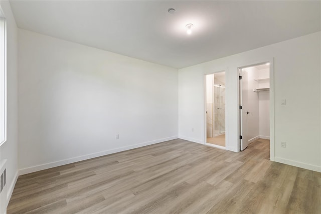 40 Singer Ave Unit 201, Spring Valley, NY 10977 - unfurnished bedroom featuring light wood-type flooring, a spacious closet, a closet, and ensuite bath