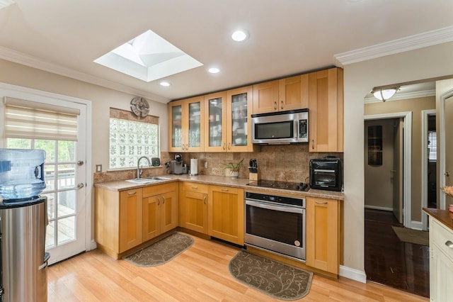 18 Hawthorne Ln, Valley Stream, NY 11581 - kitchen featuring appliances with stainless steel finishes, a skylight, a sink, crown molding, and light wood-style flooring