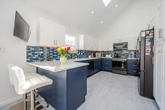 1270 Mara Ct, Atlantic Beach, NY 11509 - kitchen featuring appliances with stainless steel finishes, a peninsula, white cabinetry, decorative backsplash, and high vaulted ceiling