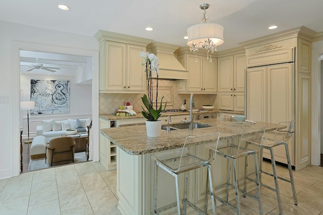 15 Old Farm Rd, Scarsdale, NY 10583 - kitchen with cream cabinets, paneled fridge, custom range hood, light stone countertops, and tasteful backsplash