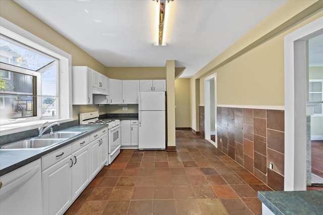 102 Broadway, Dobbs Ferry, NY 10522 - kitchen featuring white appliances, dark countertops, a sink, white cabinets, and tile walls