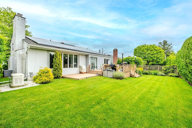 36 Randy Ln, Plainview, NY 11803 - back of property featuring a chimney, central air condition unit, roof mounted solar panels, and a wooden deck