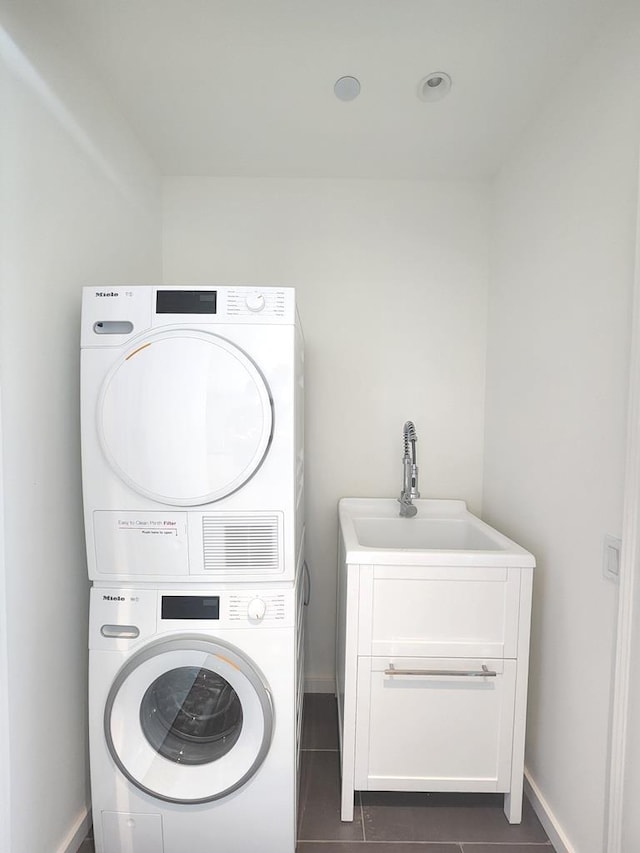 133-36 37th Ave Unit 8B, Flushing, NY 11354 - laundry room featuring stacked washer and clothes dryer, dark tile patterned floors, and baseboards