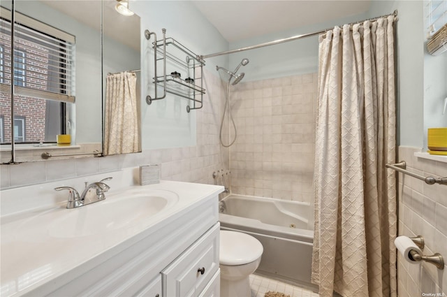 425 Shore Rd Unit 2B, Long Beach, NY 11561 - bathroom featuring toilet, tile walls, shower / bathtub combination with curtain, vanity, and a wainscoted wall