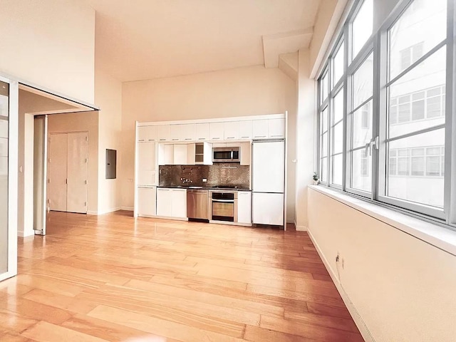 2728 Thomson Ave Unit 434, Long Island City, NY 11101 - kitchen with stainless steel appliances, white cabinetry, backsplash, dark countertops, and light wood-type flooring