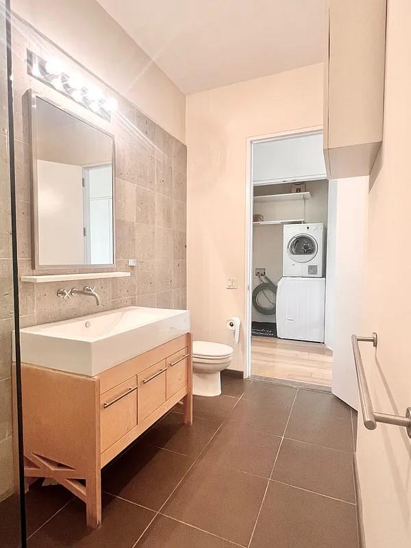 2728 Thomson Ave Unit 434, Long Island City, NY 11101 - bathroom with toilet, washer / clothes dryer, vanity, tile patterned floors, and tile walls