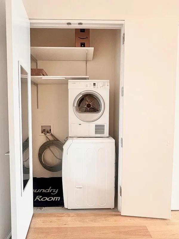 2728 Thomson Ave Unit 434, Long Island City, NY 11101 - laundry room featuring wood finished floors and stacked washing machine and dryer