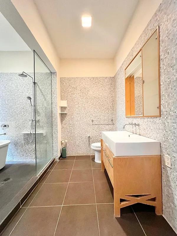2728 Thomson Ave Unit 434, Long Island City, NY 11101 - full bath with tile patterned floors, toilet, vanity, a walk in shower, and tile walls