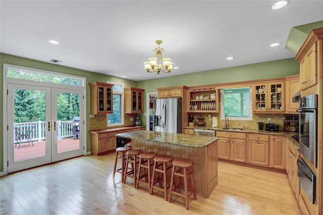 23 Knox Ave, Stony Brook, NY 11790 - kitchen featuring stainless steel appliances, a sink, a breakfast bar, backsplash, and light wood finished floors