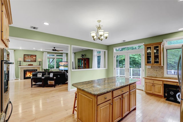23 Knox Ave, Stony Brook, NY 11790 - kitchen with light wood-type flooring, a warm lit fireplace, decorative backsplash, stone countertops, and ceiling fan