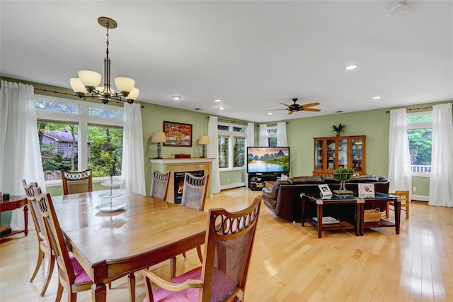 23 Knox Ave, Stony Brook, NY 11790 - dining space with a lit fireplace, recessed lighting, light wood-type flooring, a chandelier, and a ceiling fan