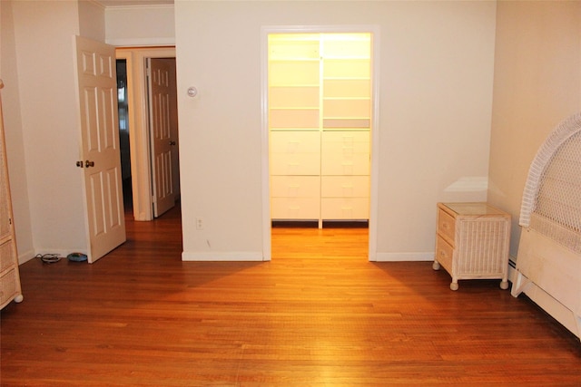 113 Pine Neck Ave, East Patchogue, NY 11772 - unfurnished bedroom featuring a walk in closet, wood finished floors, a closet, and baseboards