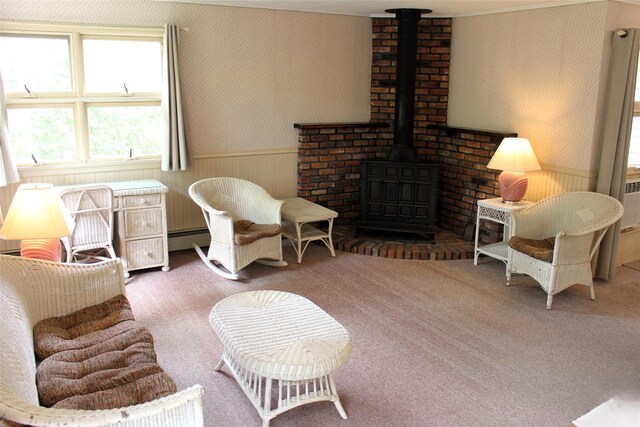 113 Pine Neck Ave, East Patchogue, NY 11772 - carpeted living area featuring wallpapered walls, a wood stove, wainscoting, and a baseboard heating unit