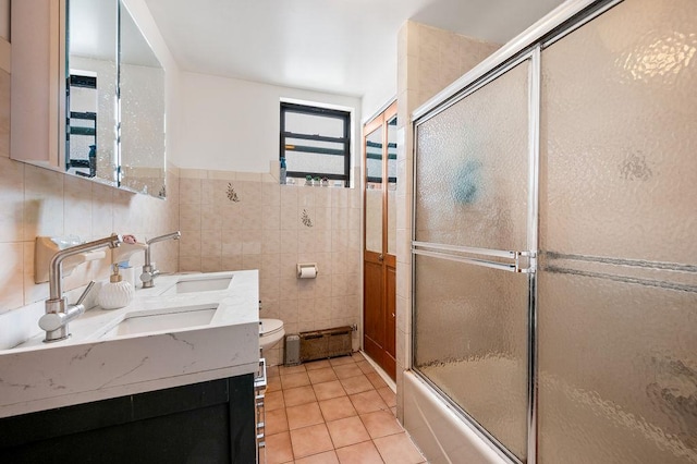34-15 91st St, Jackson Heights, NY 11372 - bathroom featuring tile walls, double vanity, toilet, bath / shower combo with glass door, and tile patterned floors