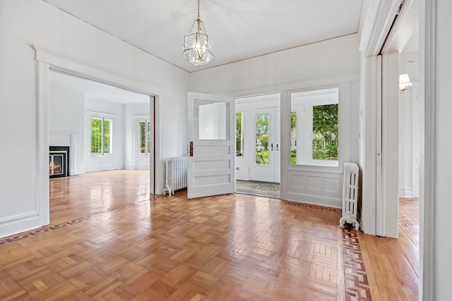 158 Loring Ave, Pelham, NY 10803 - foyer entrance featuring radiator heating unit, a chandelier, a glass covered fireplace, and a decorative wall