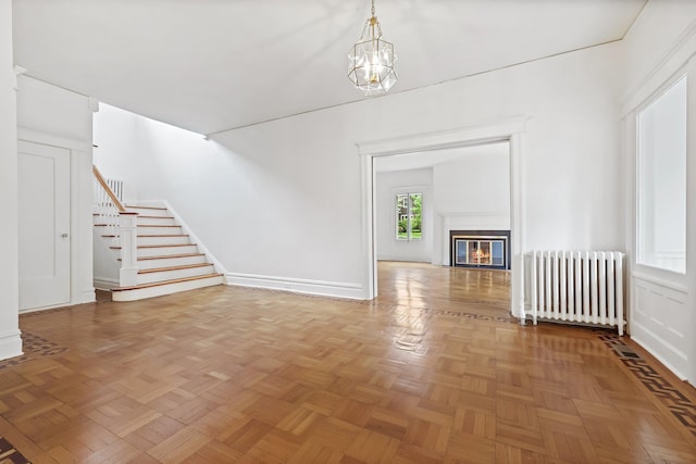 158 Loring Ave, Pelham, NY 10803 - unfurnished living room featuring radiator heating unit, stairs, a chandelier, baseboards, and a glass covered fireplace