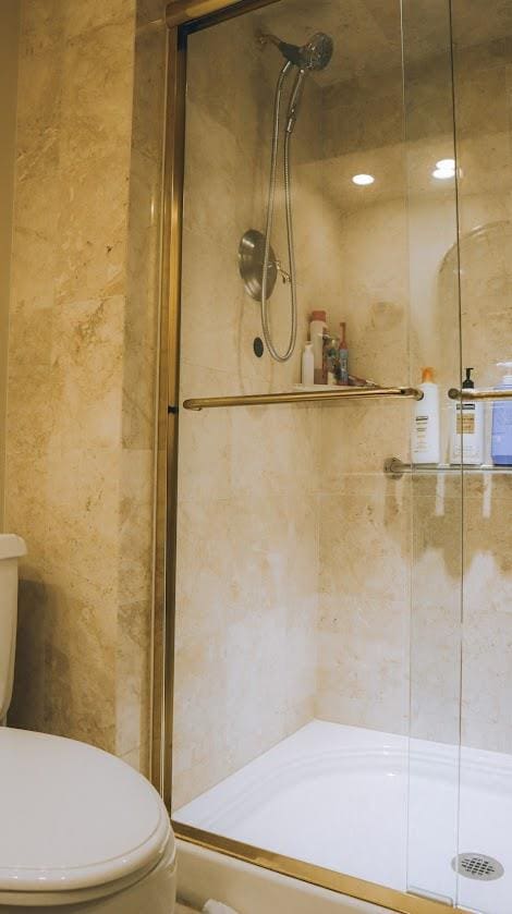 200 High Point Dr Unit 302, Hartsdale, NY 10530 - bathroom featuring toilet, a shower stall, and tile walls