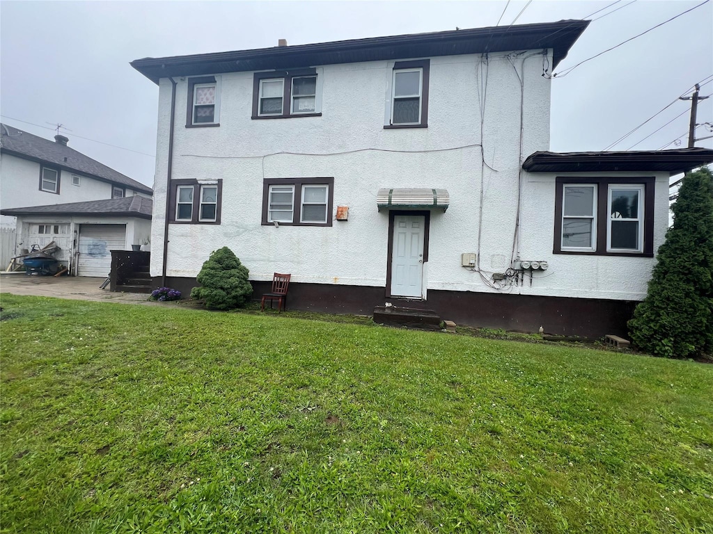70 W End Ave, Inwood, NY 11096 - view of front facade featuring a front yard, an outdoor structure, stucco siding, and a garage