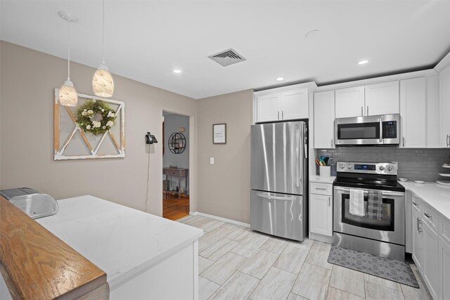 7 Pilgrim Ln, Washingtonville, NY 10992 - kitchen featuring appliances with stainless steel finishes, backsplash, hanging light fixtures, recessed lighting, and light stone countertops