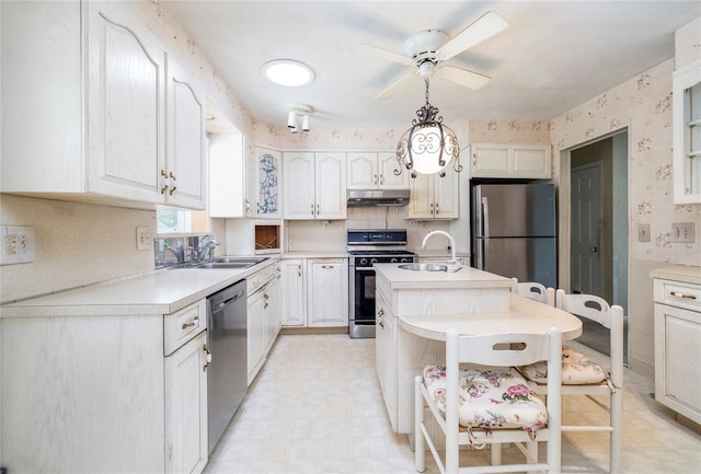 810 Tooker Ave, West Babylon, NY 11704 - kitchen featuring appliances with stainless steel finishes, under cabinet range hood, light countertops, a ceiling fan, and wallpapered walls